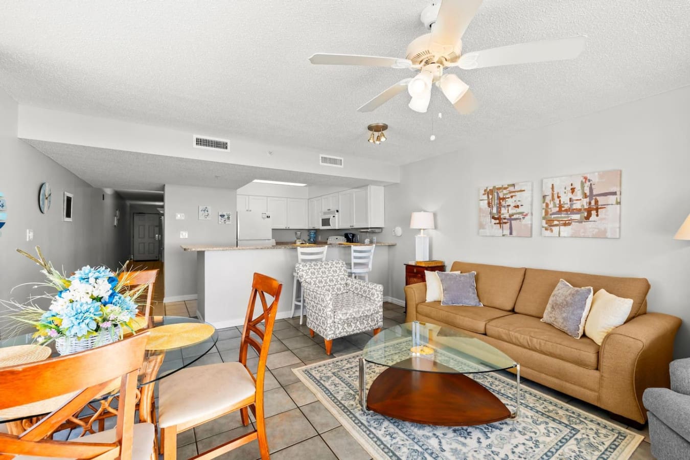 This open-concept living space is basically the perfect setup for a beach vacation—kitchen, dining, and living room all flowing together so you can cook, eat, lounge, and watch the ocean without ever really leaving your spot.