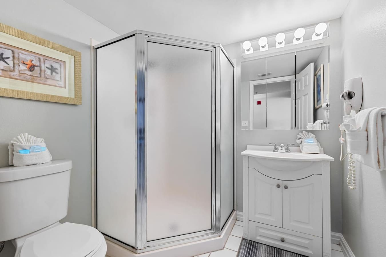 This bright, efficient bathroom has everything you need to freshen up between beach days—clean white fixtures, great lighting, and that shower setup that'll rinse the sand away so you can get right back out there.