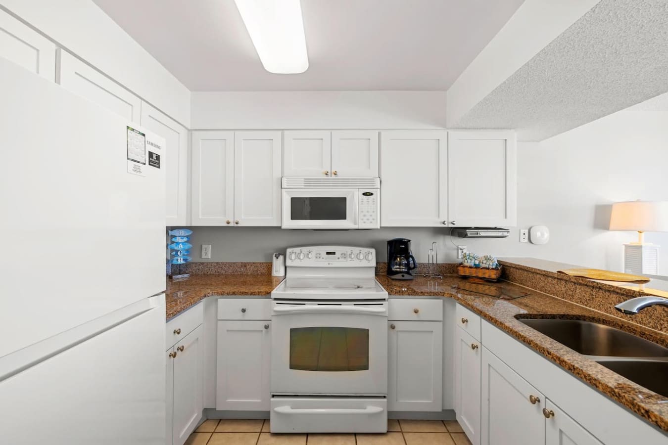 This bright, efficiently-designed kitchen has everything you need to whip up meals without spending your whole vacation indoors—white cabinetry, granite countertops, and stainless steel appliances that make cooking feel like part of the vacation rather th