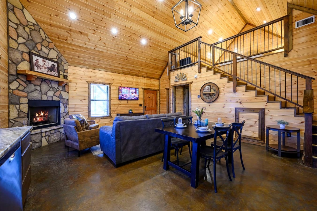 This spacious open-concept cabin features soaring wood ceilings, a stone fireplace, and a loft overlooking the main living area.