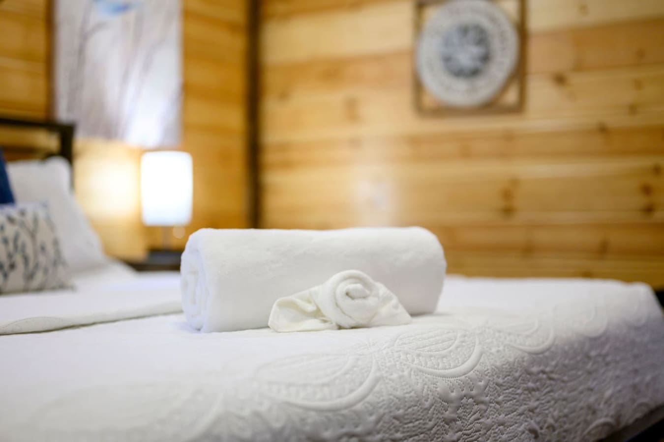 Cozy cabin bedroom with warm wood walls, soft lighting, and those perfectly rolled towels that make you feel like you're actually on vacation.