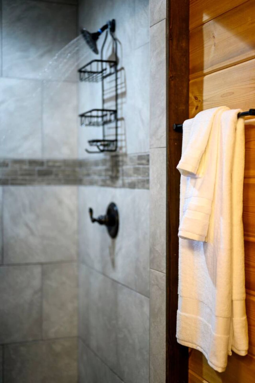 The shower features sleek tile work, a rainfall showerhead, and built-in shelving for all your essentials.