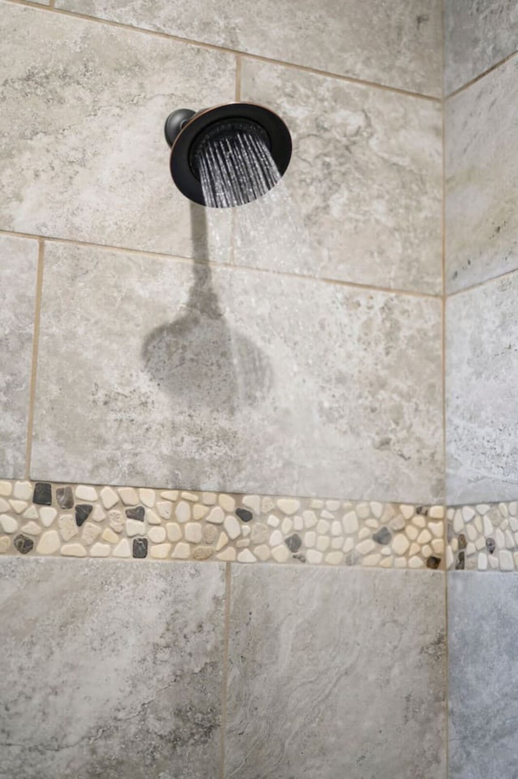 This shower's got that spa vibe with the rainfall head and natural stone tile work.