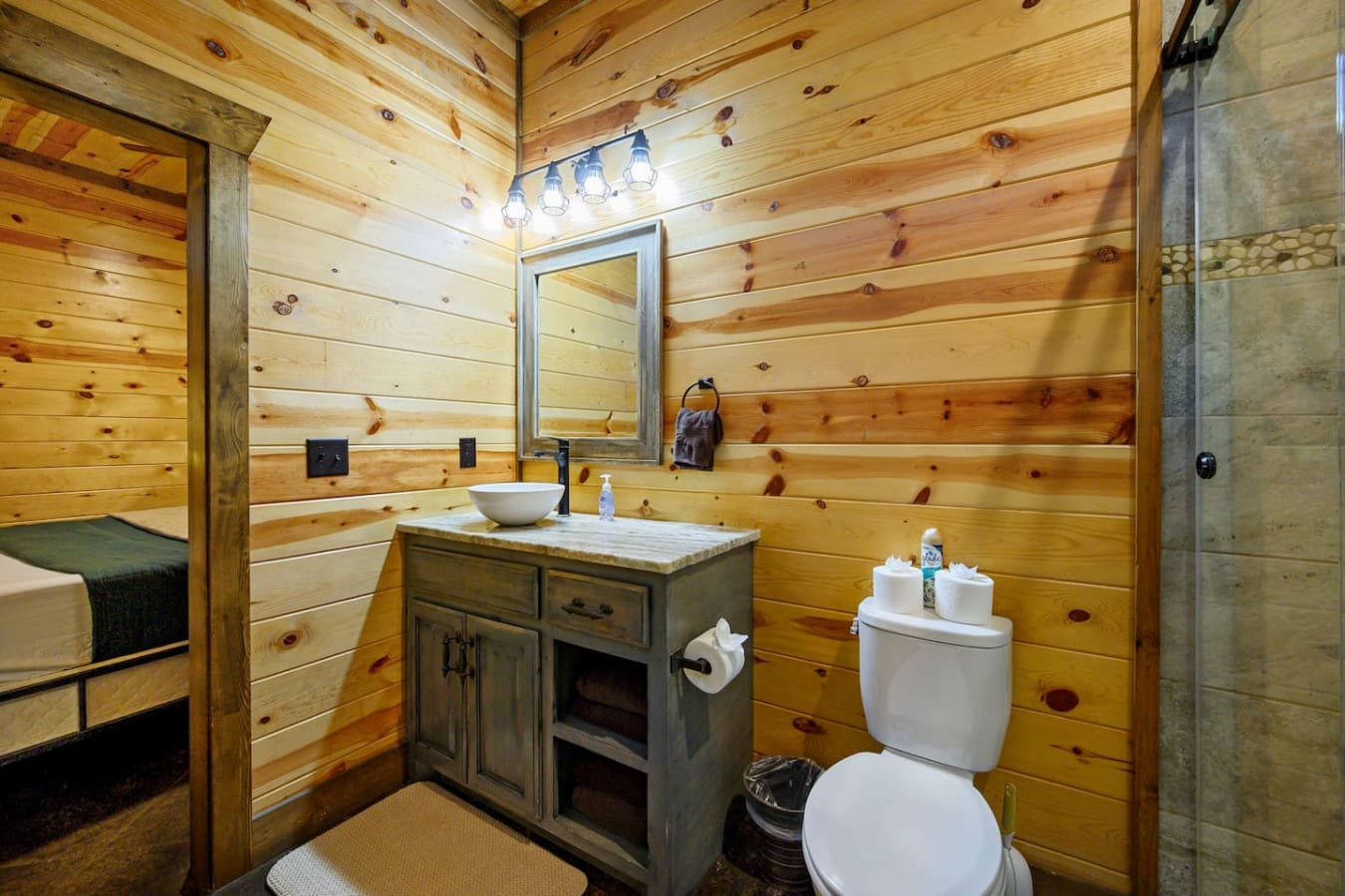 This cozy log cabin bathroom features rustic wood walls, a vessel sink vanity, and modern fixtures for a charming retreat vibe.
