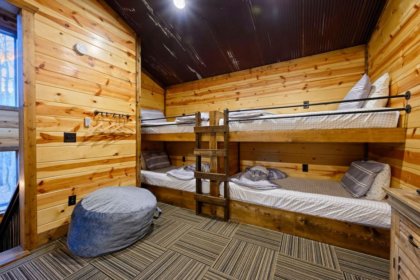 Cozy cabin bunkroom with multiple beds and rustic wood finishes, perfect for families or groups.