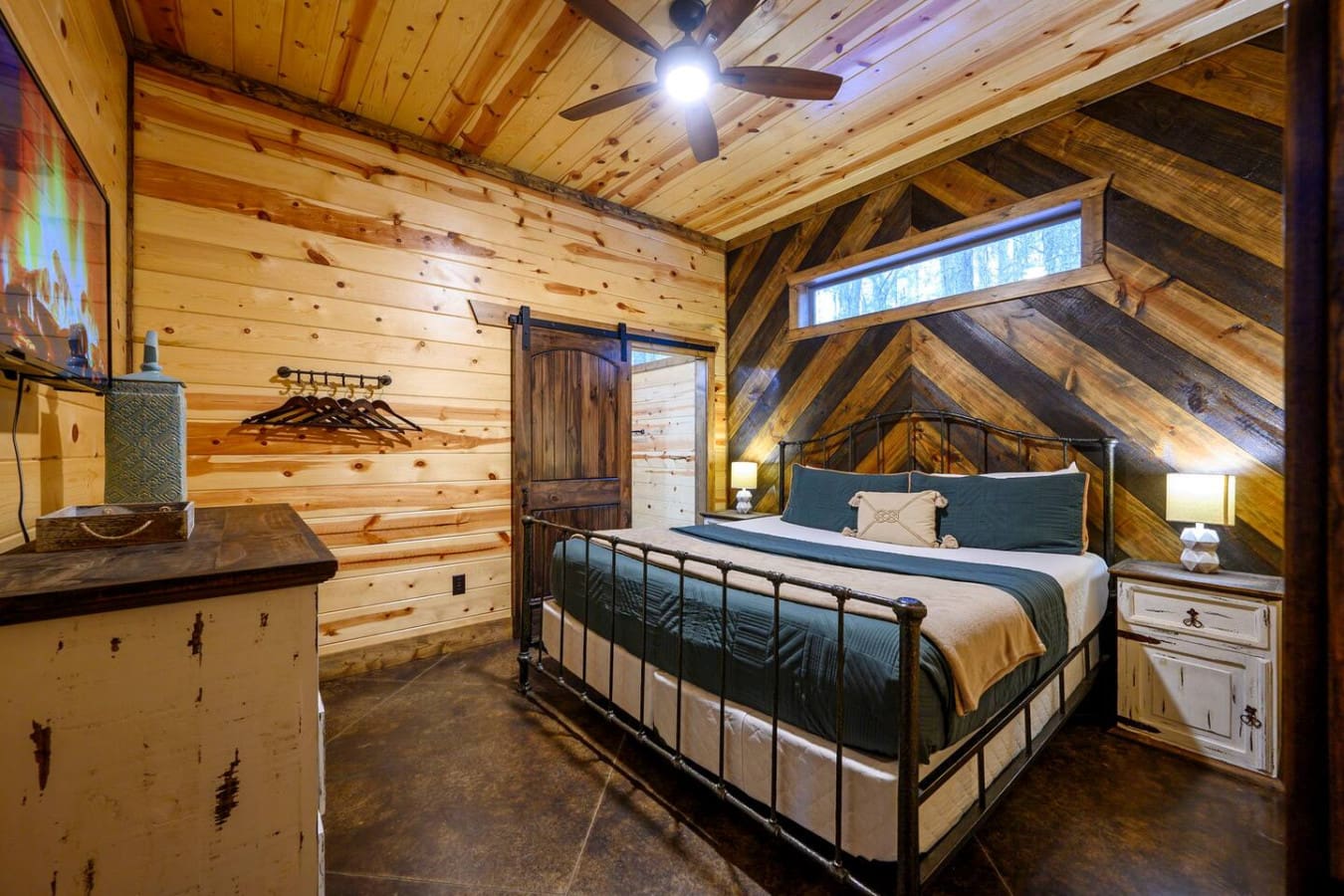 This cozy log cabin bedroom features exposed beams, a metal bed frame, and plenty of natural wood charm throughout.