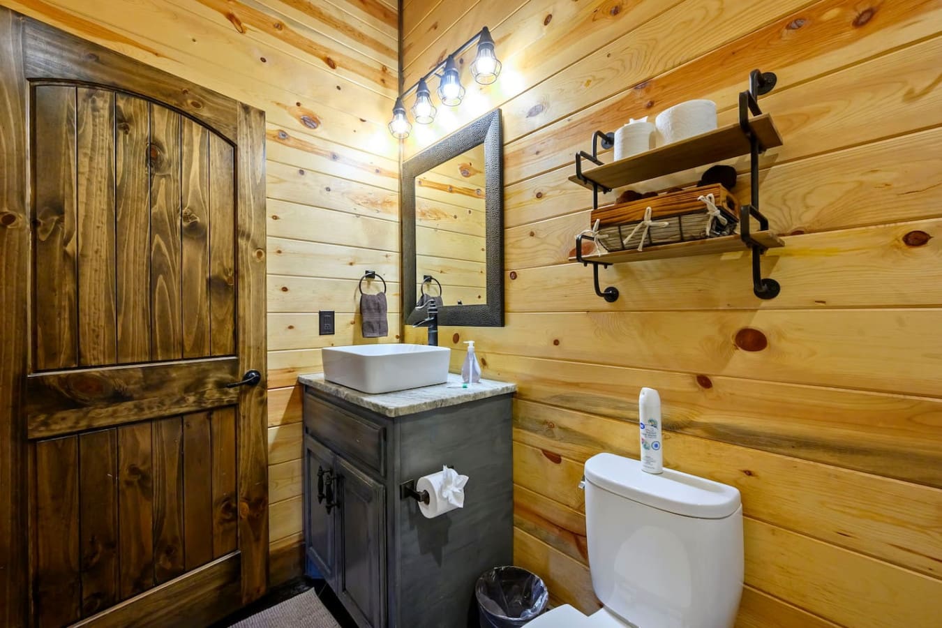 This rustic cabin bathroom features a stylish vessel sink, modern toilet, and walk-in shower with all the cozy wood charm.