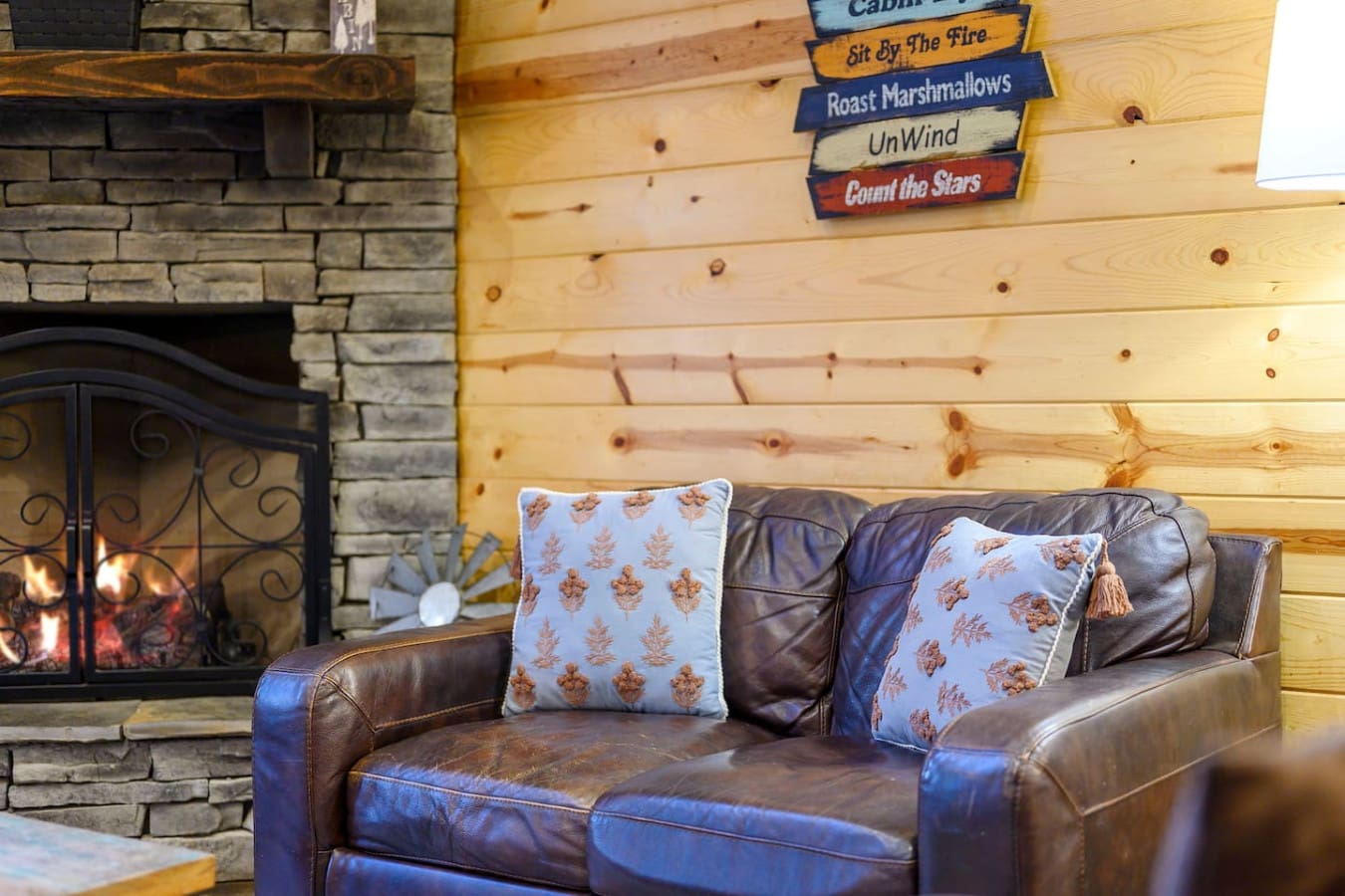 Cozy leather sofa by the fireplace in our log cabin living room, perfect for unwinding after a day outdoors.