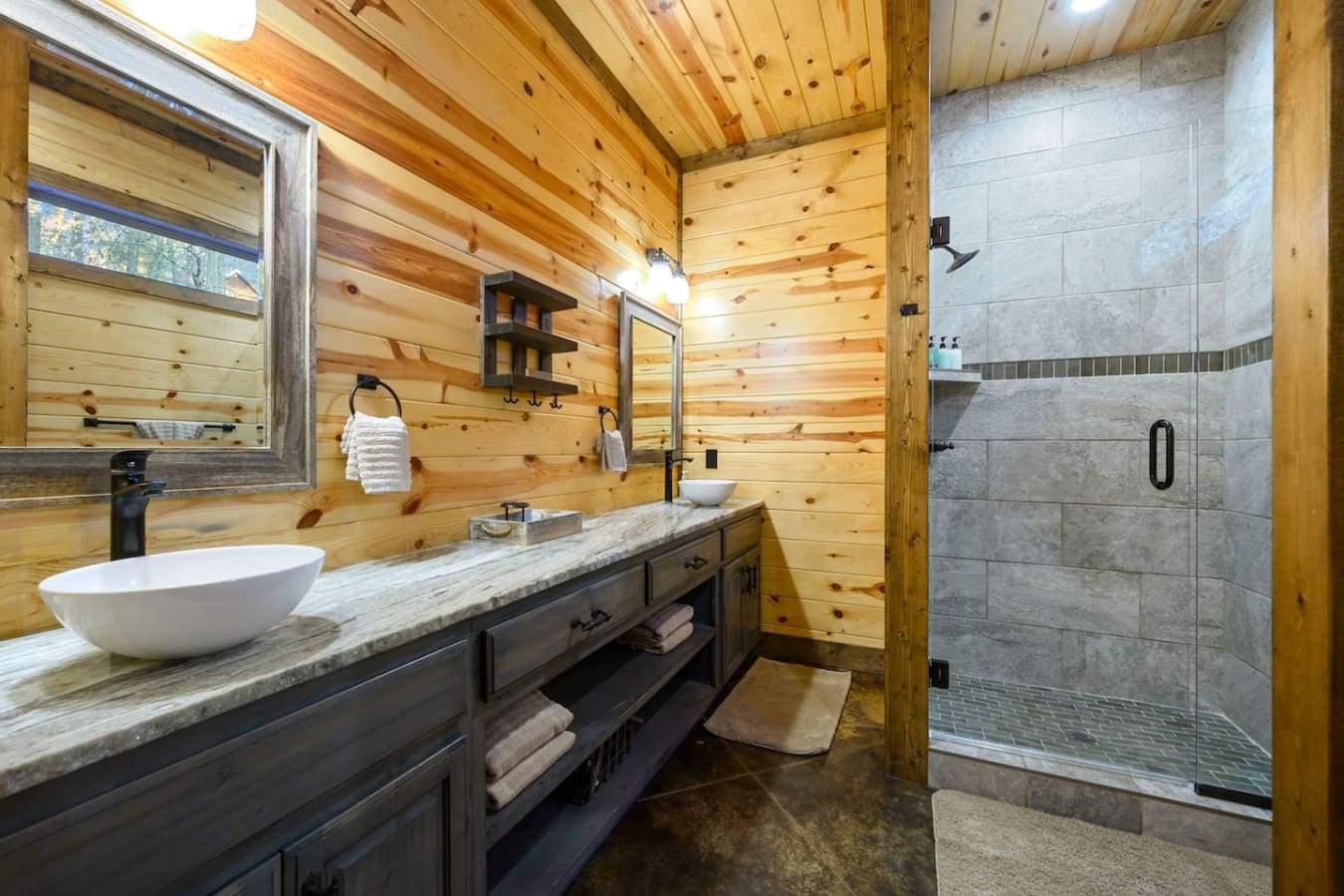 This rustic-modern primary bathroom features a spacious walk-in shower, dual vanity, and soaring wood-beam ceilings.