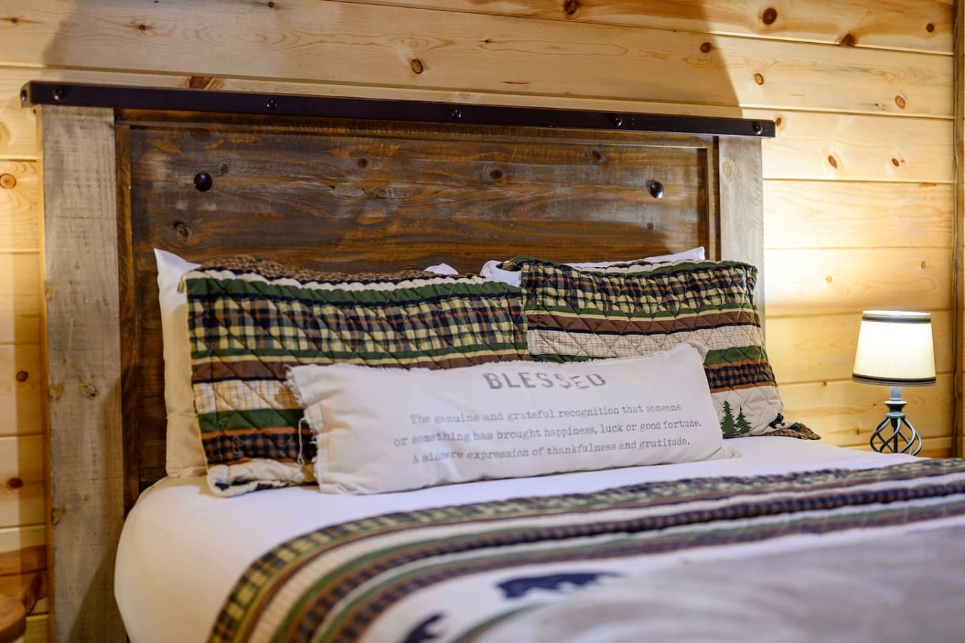 Cozy wood cabin bedroom with rustic headboard and plaid bedding that feels like a warm mountain retreat.
