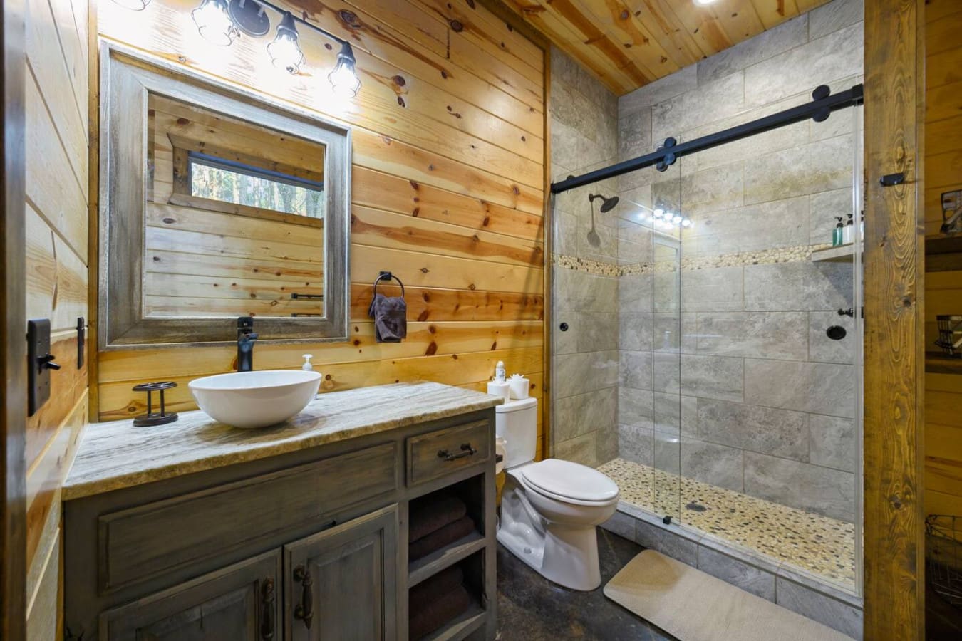 This rustic cabin bathroom features a spa-like shower with heated floors and a statement vessel sink.