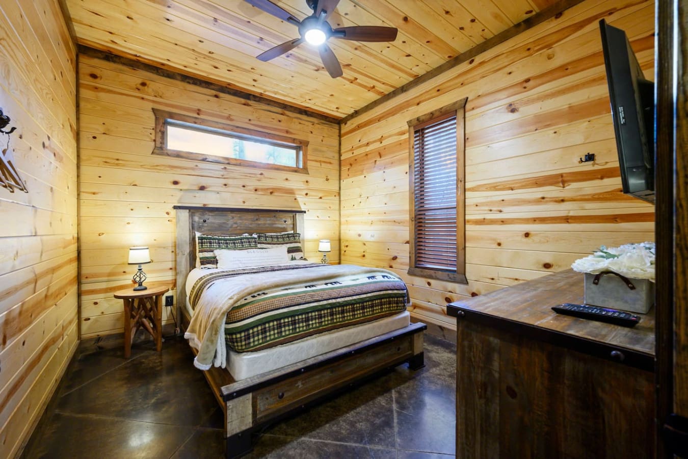 Cozy wood cabin bedroom with a comfy bed, flat-screen TV, and that perfect rustic getaway vibe.