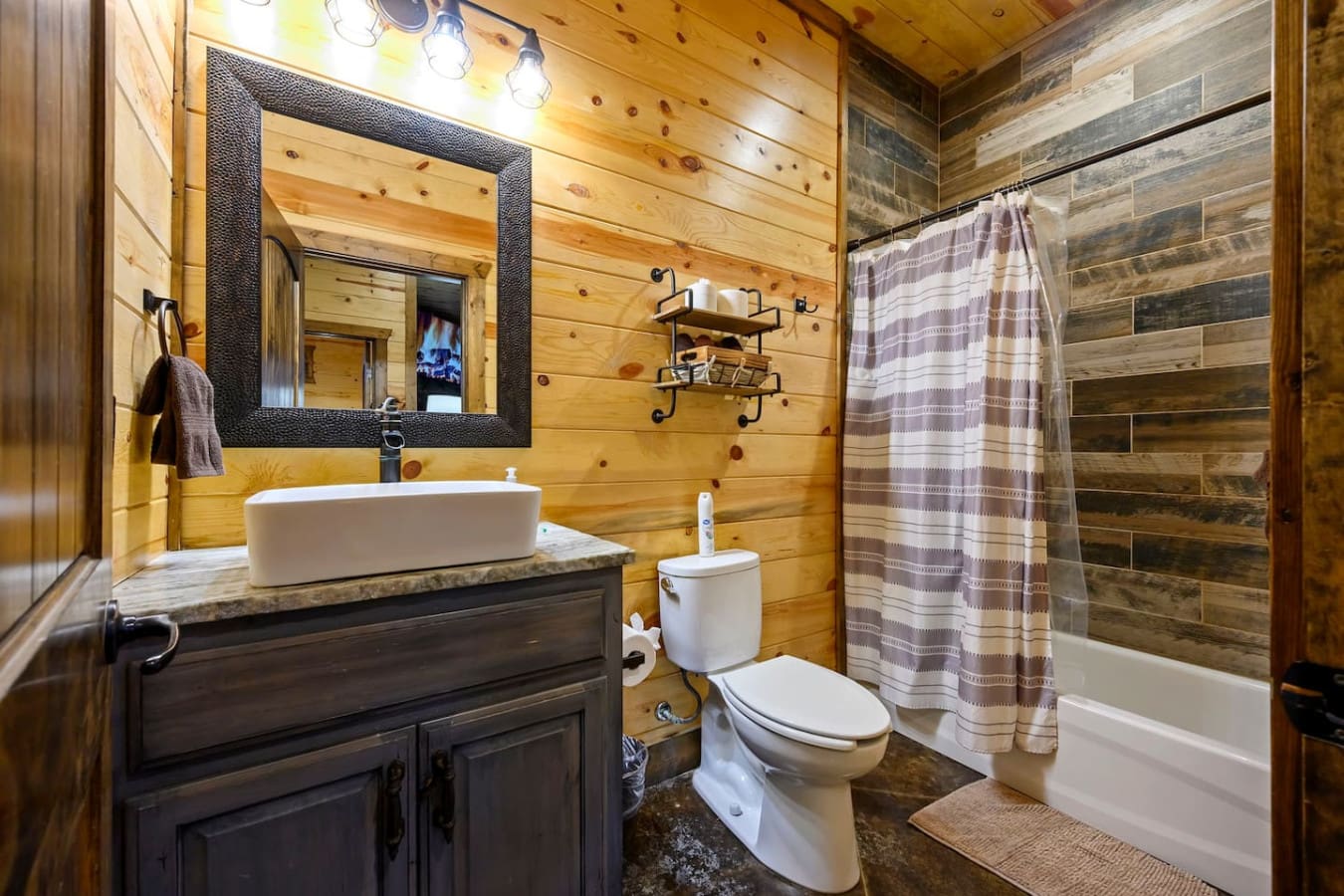 This rustic cabin bathroom features a stylish vessel sink, modern fixtures, and a relaxing soaking tub with tile surround.