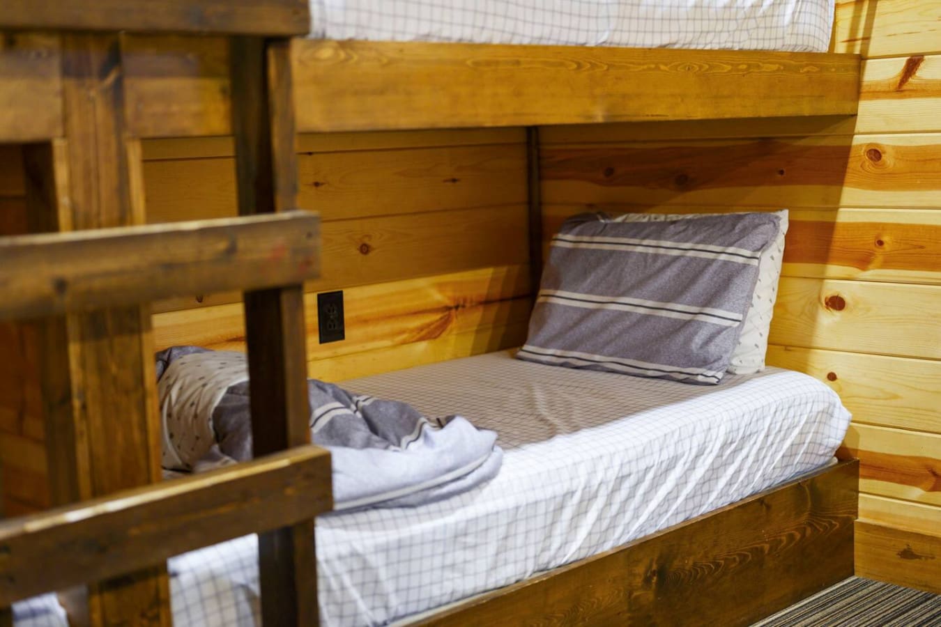 Cozy wooden bunk beds with fresh linens in a rustic cabin bedroom.