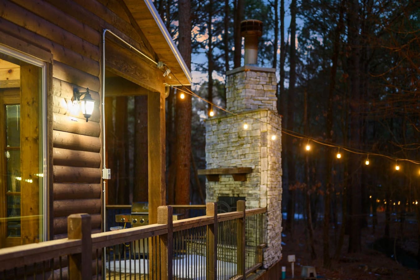 Cozy evenings on the deck with string lights and that beautiful stone chimney glowing in the forest darkness.