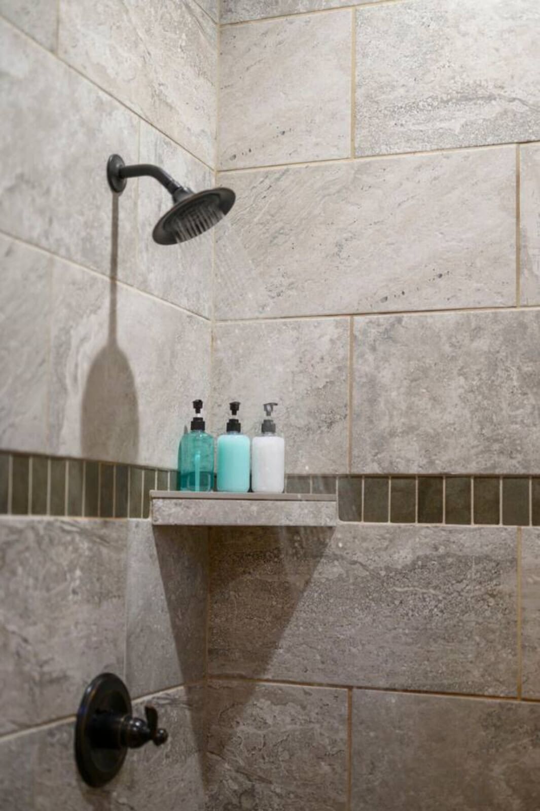 Spa-like shower with travertine tile and rainfall showerhead for the ultimate relaxation.