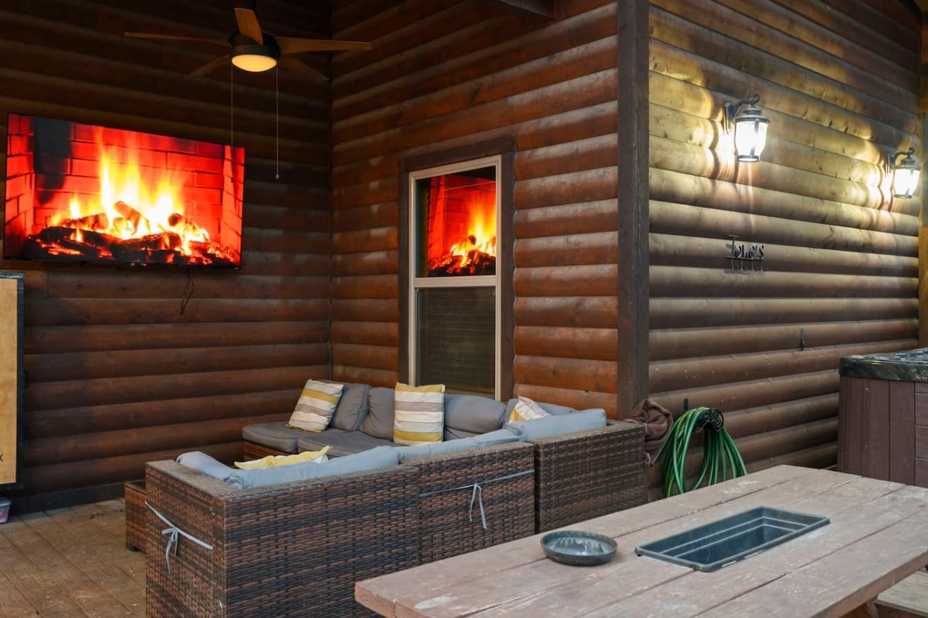 Cozy covered patio with a fireplace TV, comfortable seating, and ambient lighting perfect for evening hangouts.