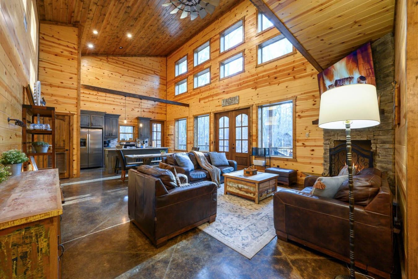 This stunning open-concept log cabin features soaring ceilings, a stone fireplace, and walls of windows overlooking the mountains.