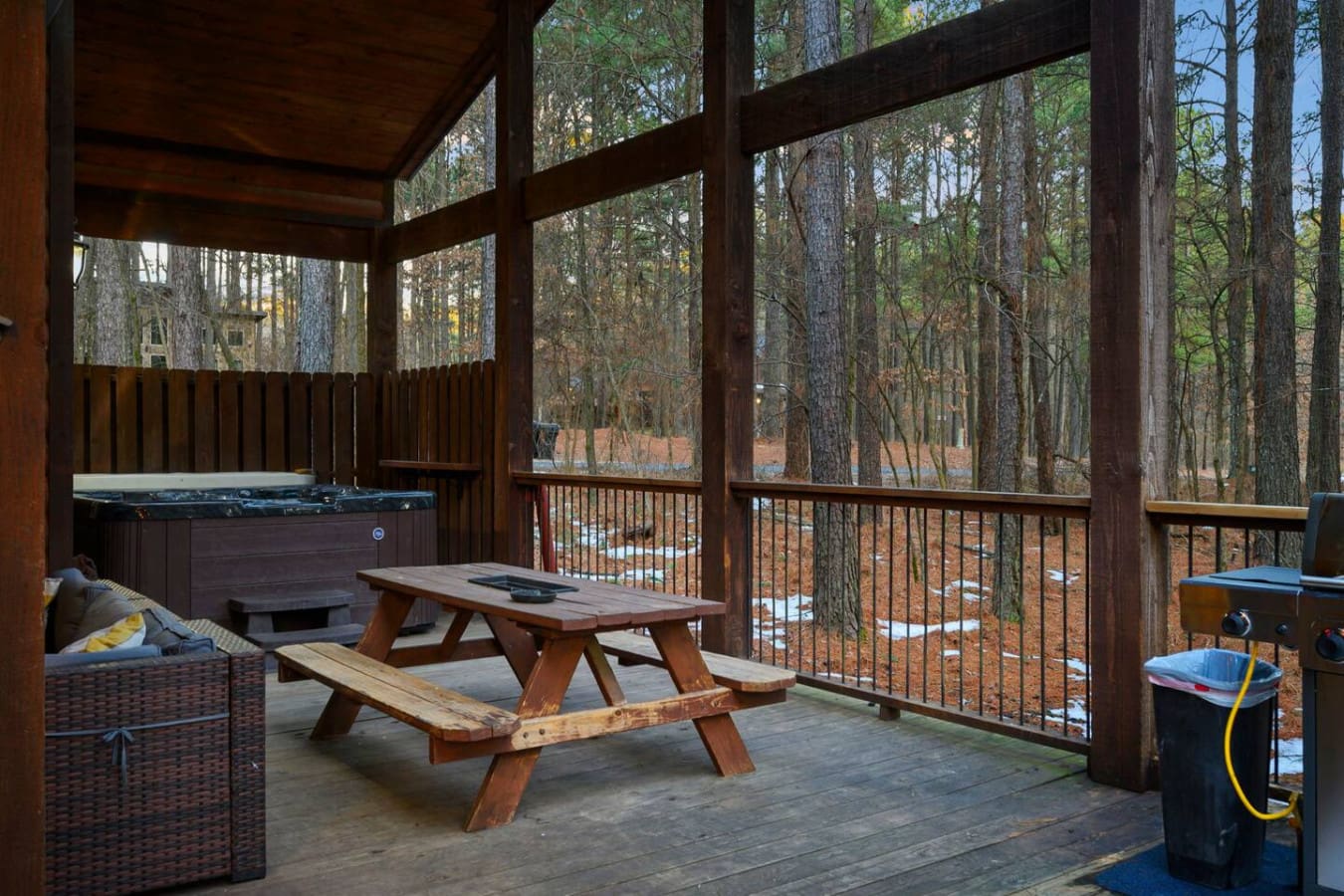 This screened deck is basically an outdoor living room with a hot tub, picnic table, and forest views for days.