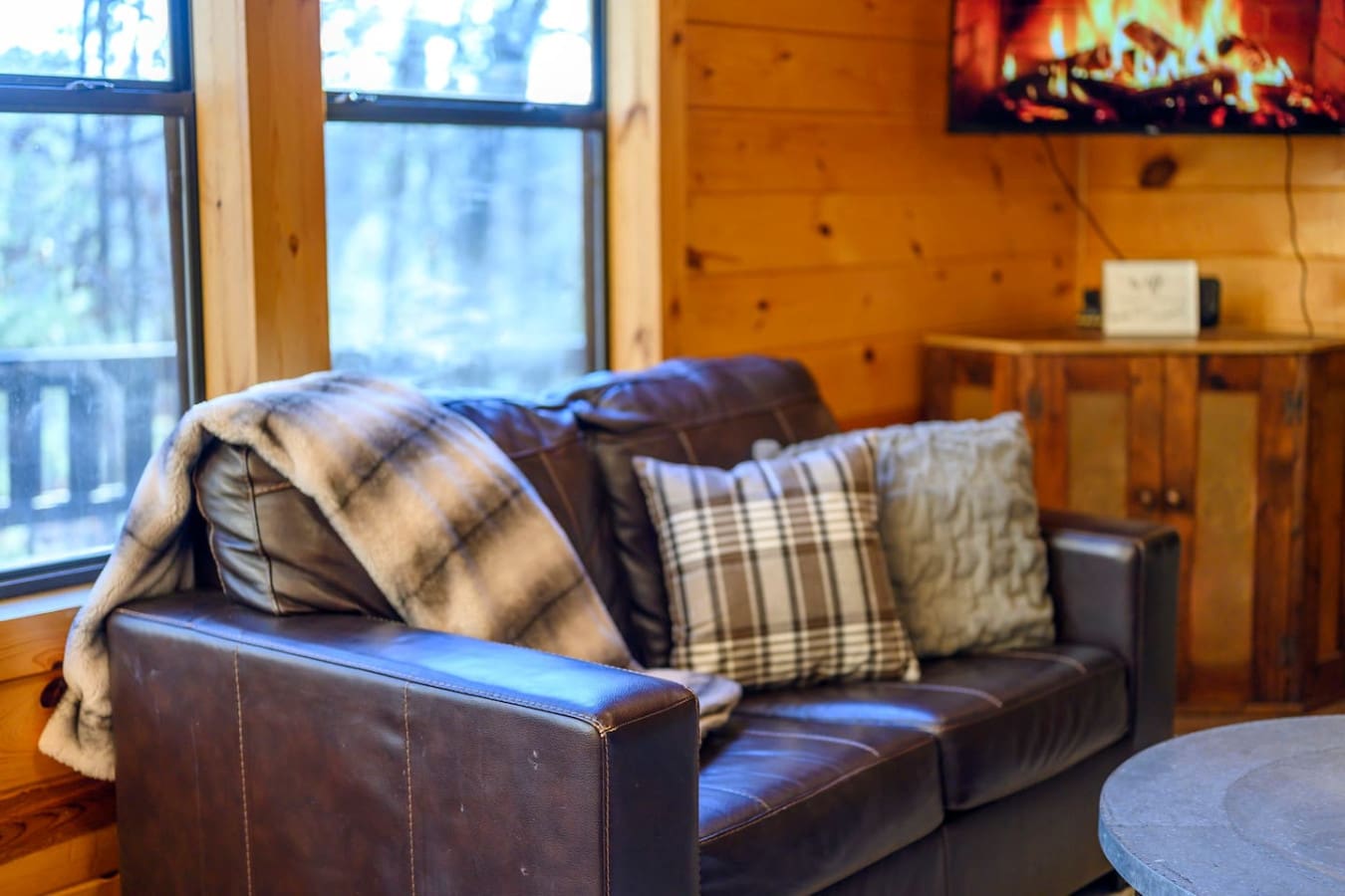 Cozy leather sofa with plaid pillows and mountain views through those massive windows—perfect for unwinding after a day outside.