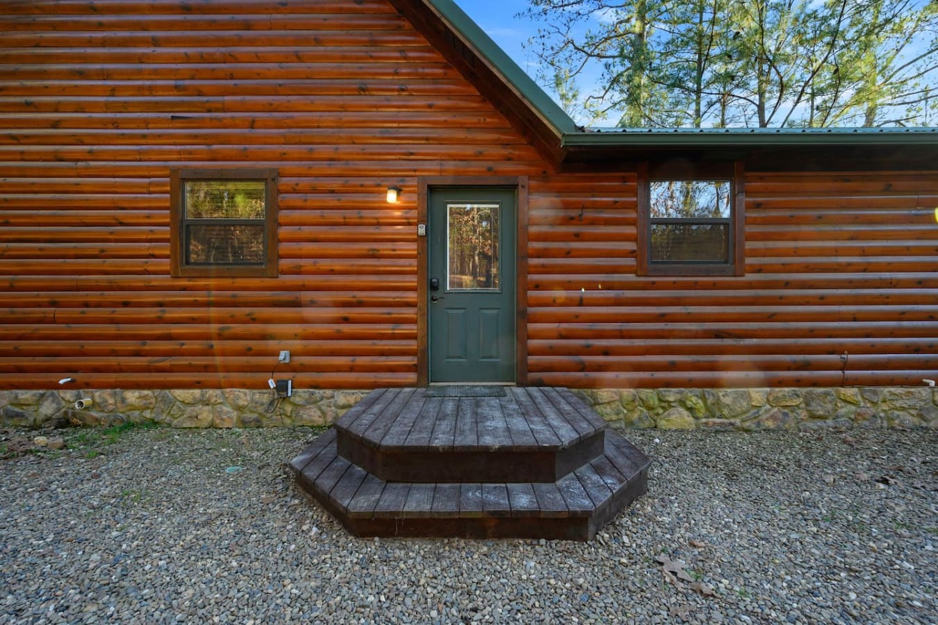 Charming log cabin with a cozy front entrance and those big windows framing the peaceful forest views.