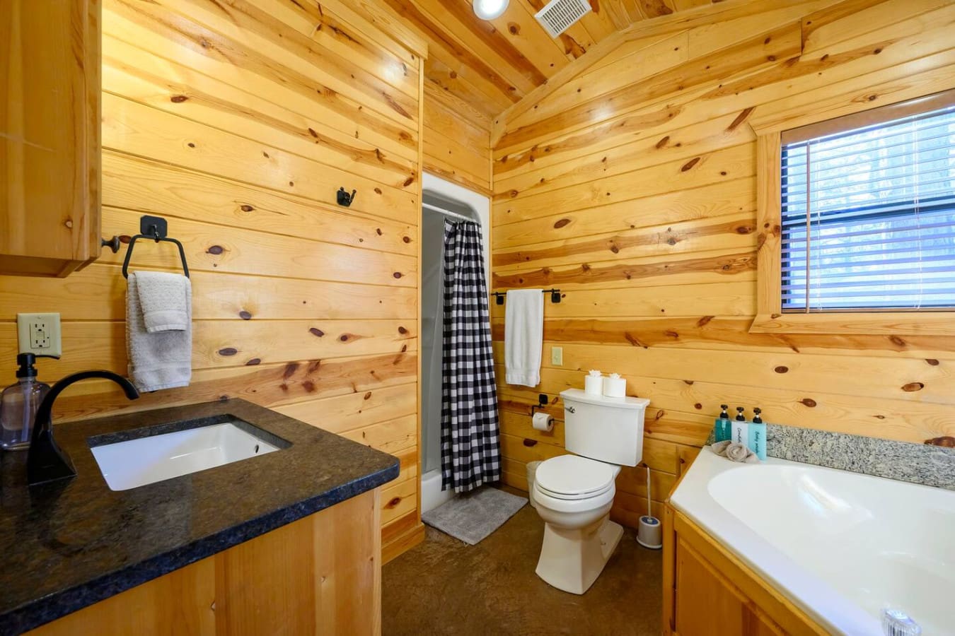 This cozy log cabin bathroom features a soaking tub, dual vanity, and plenty of rustic charm throughout.