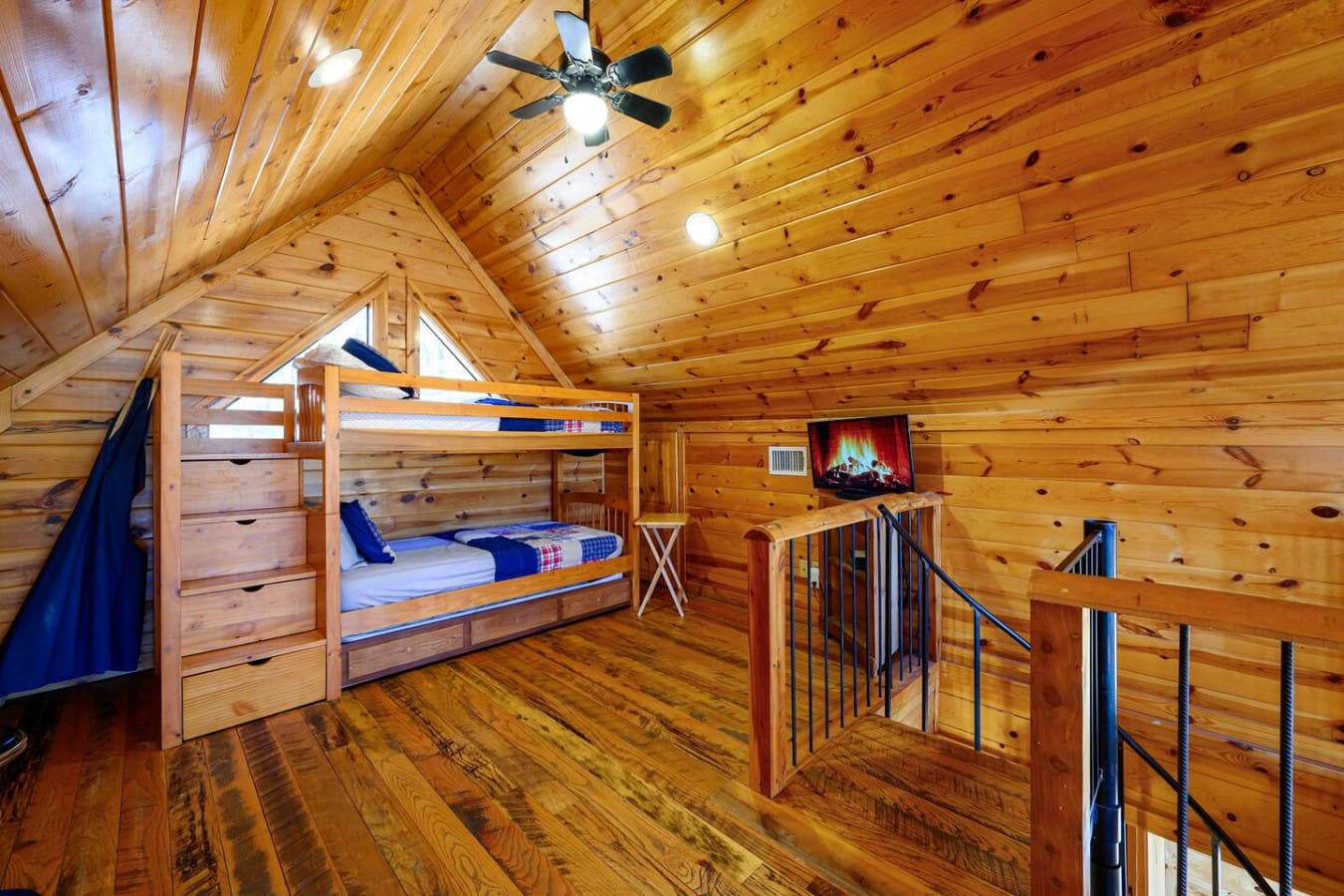 This cozy loft bedroom features a built-in bunk bed, fireplace TV, and plenty of natural wood charm perfect for families.