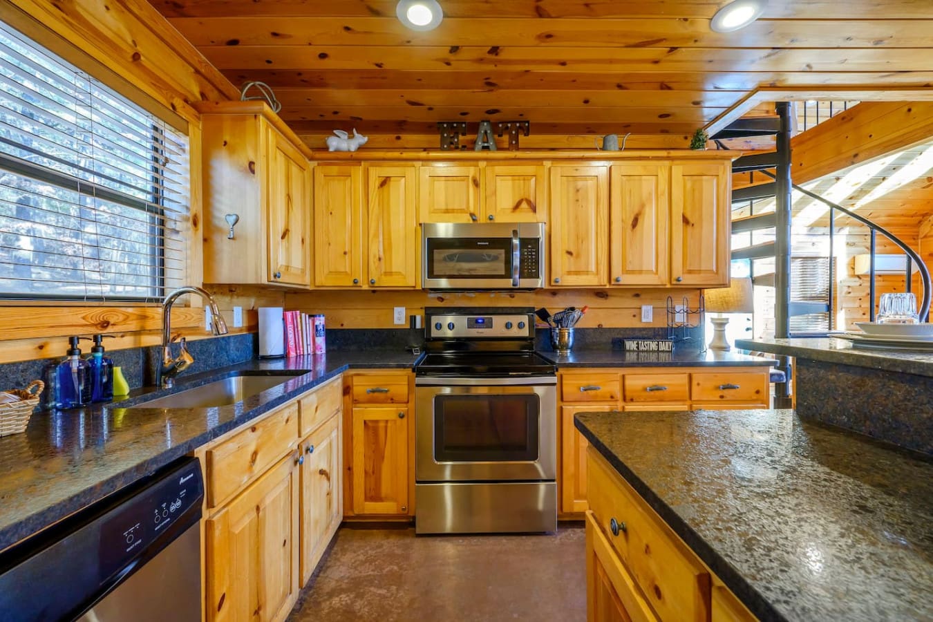 This spacious knotty pine kitchen features granite countertops, stainless steel appliances, and plenty of cooking space.