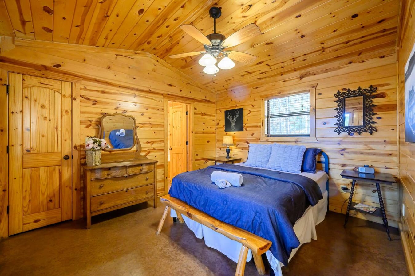 This cozy log cabin bedroom features knotty pine walls, a comfy queen bed, and all the rustic charm you need to unwind.