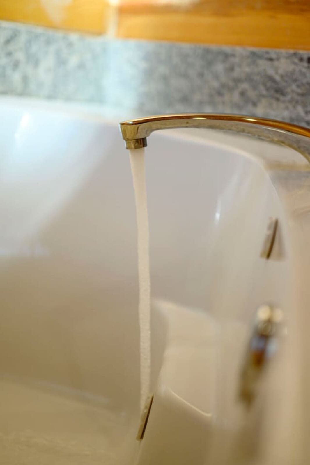 Luxe gold faucet detail in a pristine bathroom with modern finishes and natural light.