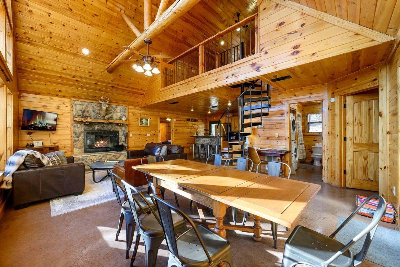 This spacious open-concept cabin has everything you need with a cozy fireplace, dining area, and loft bedroom all in one stunning wood-beamed room.