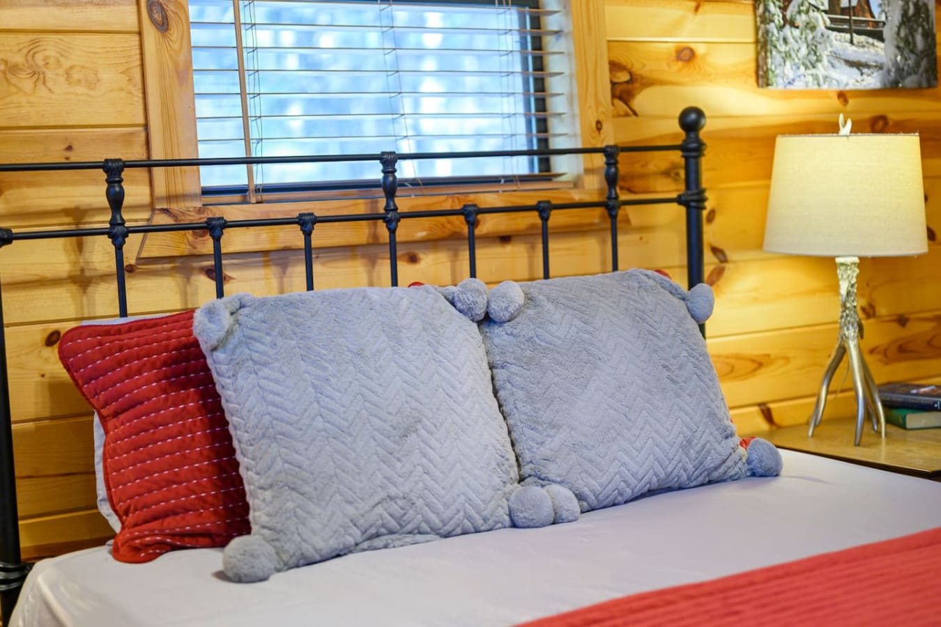 Cozy log cabin bedroom with a wrought iron bed and natural wood walls flooded with natural light.