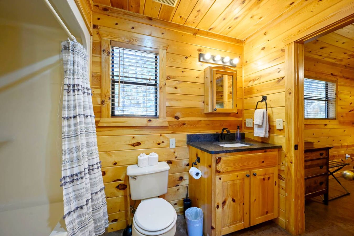 This cozy cabin bathroom features warm knotty pine throughout with a full vanity and modern fixtures.