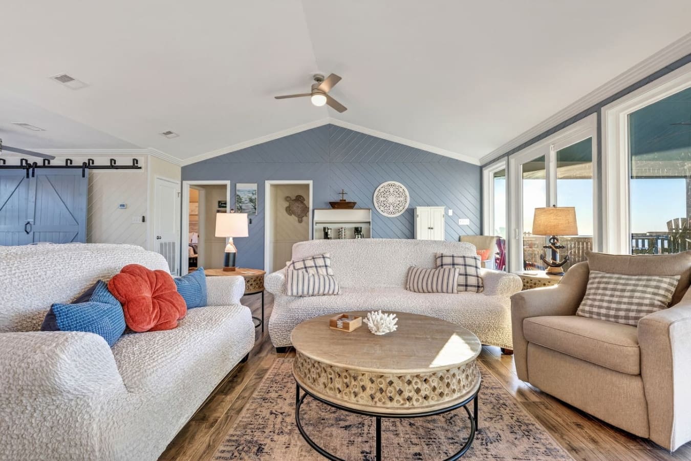 This open-concept master suite features a cozy sitting area with ocean views and a vaulted ceiling with cathedral-style shiplap.