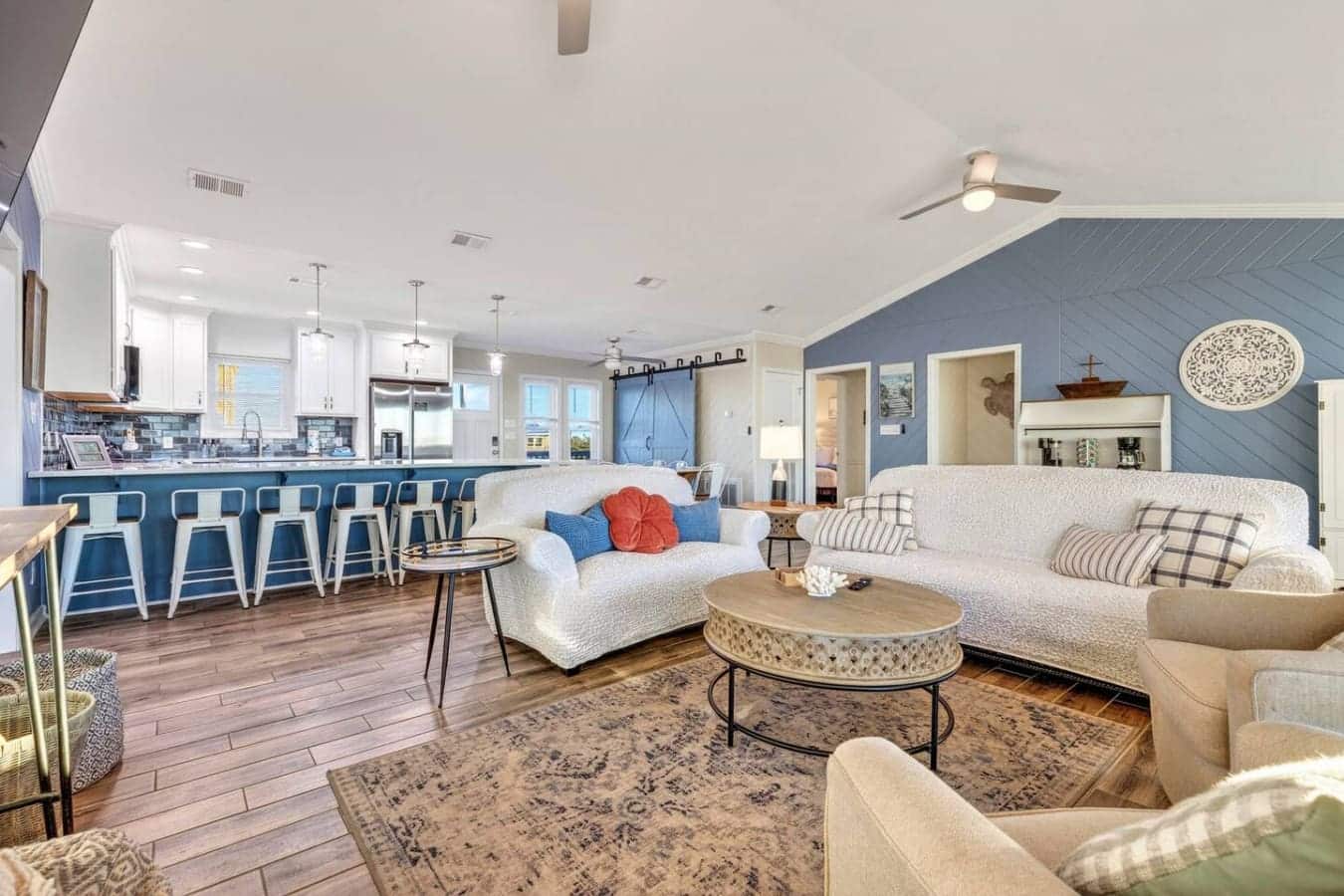 Open-concept living with gorgeous blue accent wall, white furnishings, and ocean views throughout this stunning coastal home.