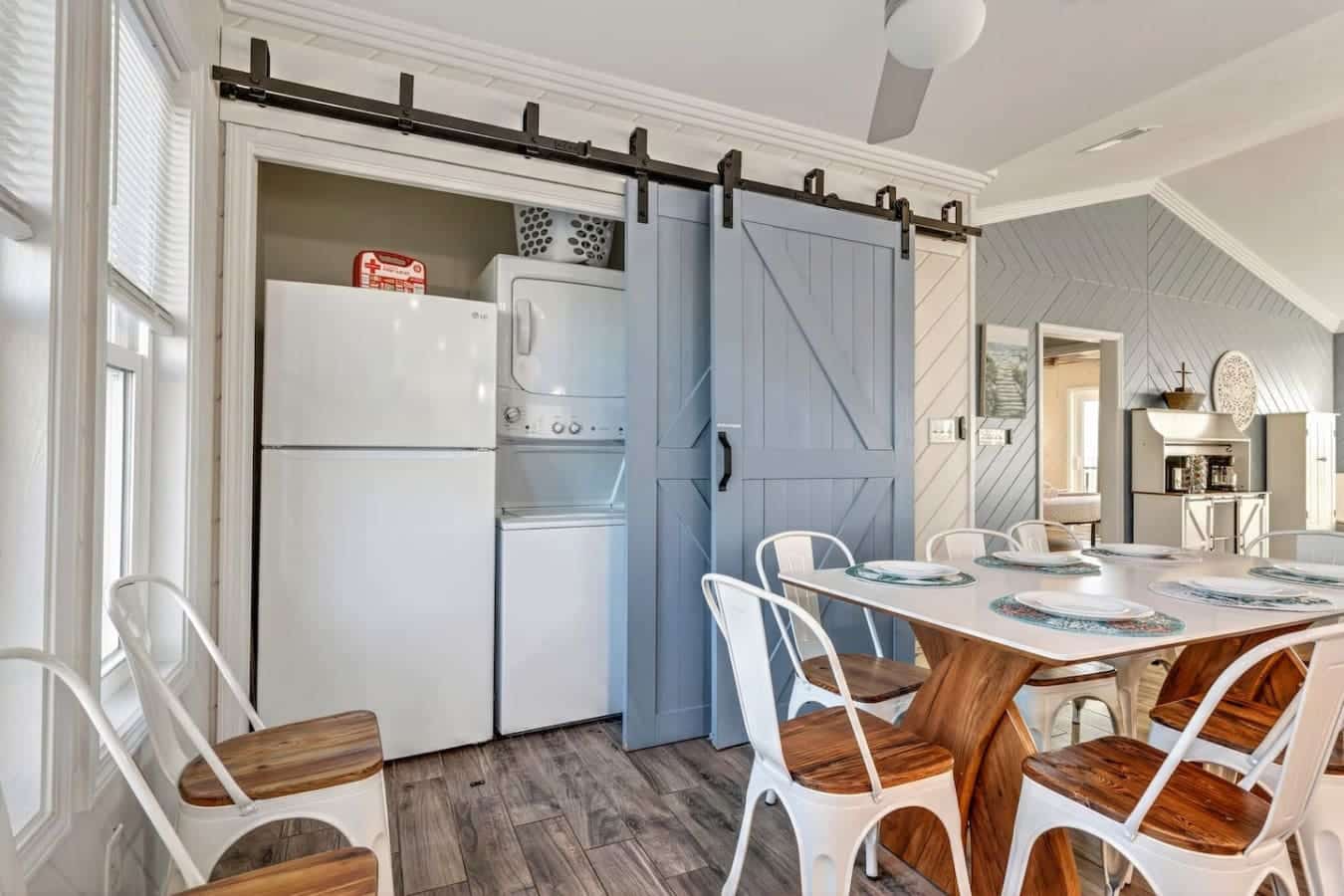 This bright, modern kitchen and dining area features sleek appliances, a sliding barn door, and plenty of space for the whole group.
