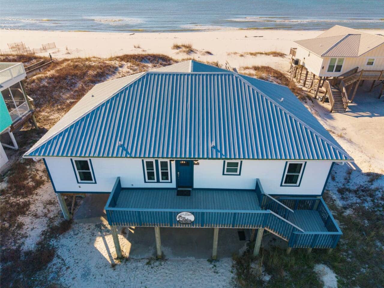 This stunning beachfront home features a massive blue metal roof and sits right on the sand with direct ocean views.