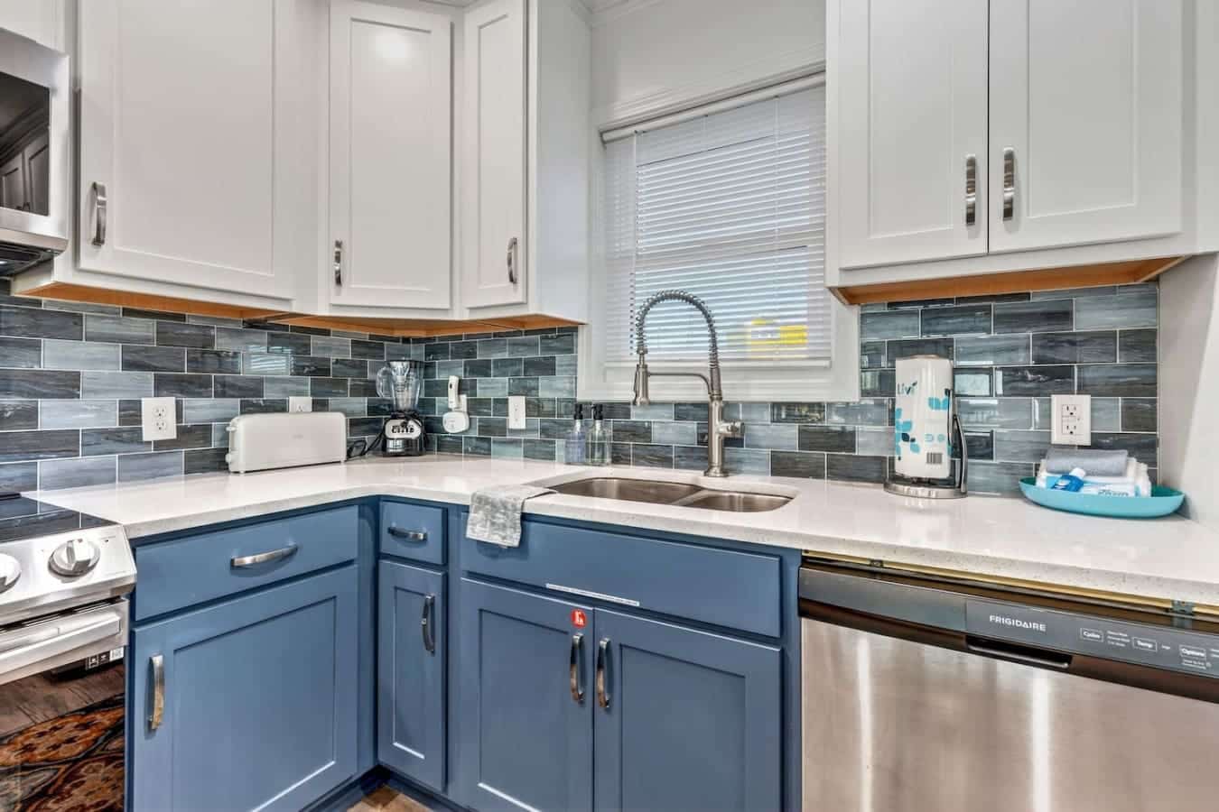 This stunning kitchen features a two-tone cabinetry design with white uppers, blue lowers, and sleek stainless steel appliances.