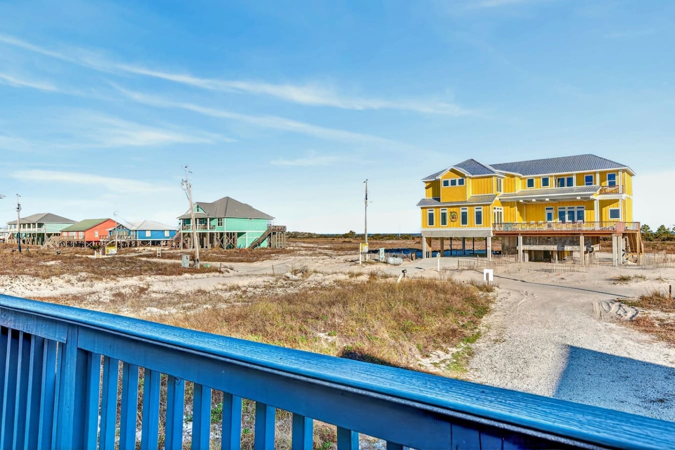 Colorful beachfront homes on stilts with wide-open ocean views and pristine sandy shores.