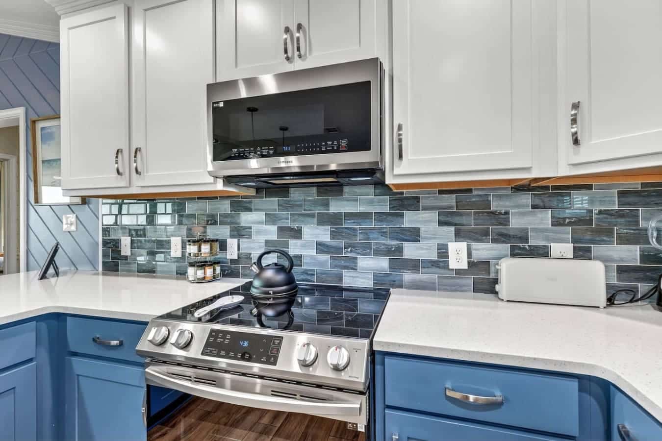 This modern kitchen features sleek stainless steel appliances, crisp white cabinetry, and a gorgeous blue-gray tile backsplash.