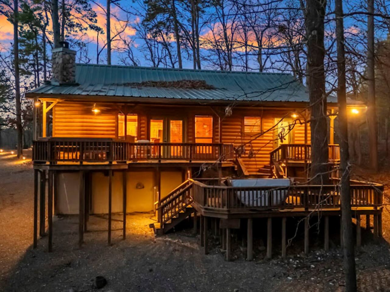 Cozy log cabin nestled in the woods with wraparound decks and warm lighting perfect for a peaceful getaway.