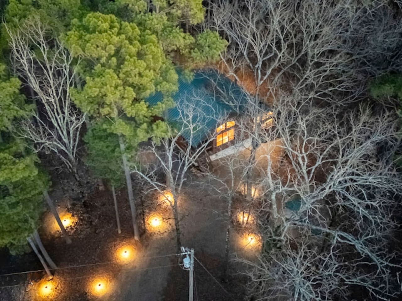 Cozy cabin nestled in the woods with ambient lighting, a peaceful pond view, and that magical forest escape feeling.