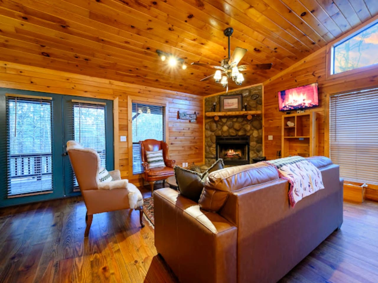 This cozy wood cabin bedroom has everything you need with a fireplace, comfy leather seating, and a flat-screen TV.