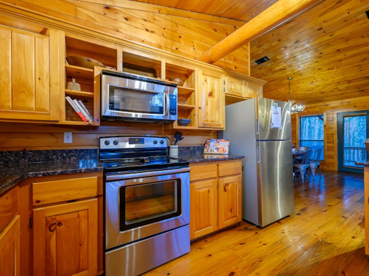 This cozy log cabin kitchen features stainless steel appliances and plenty of wood cabinetry with natural views.