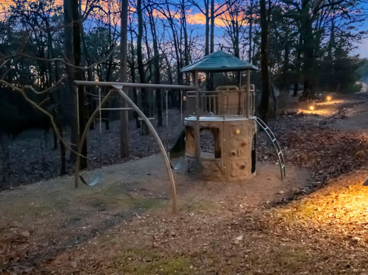 Wooded playground with a fun climbing tower structure and swing set, perfect for keeping the kids entertained.