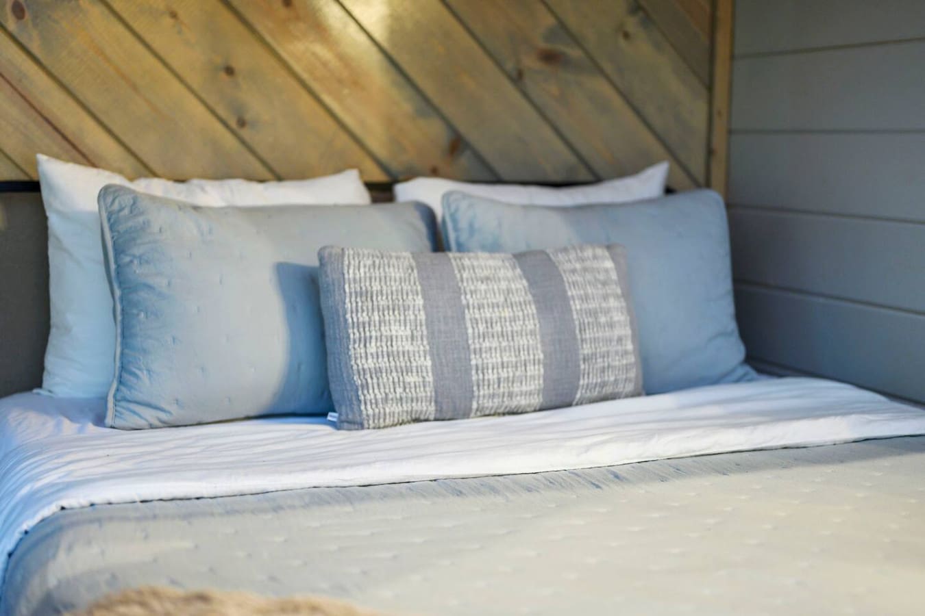 Cozy bed with crisp linens and a rustic wooden headboard that hits different in natural light.