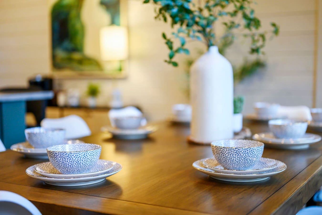 The dining room features elegant blue and white tableware set on a warm wood table with plenty of natural light.