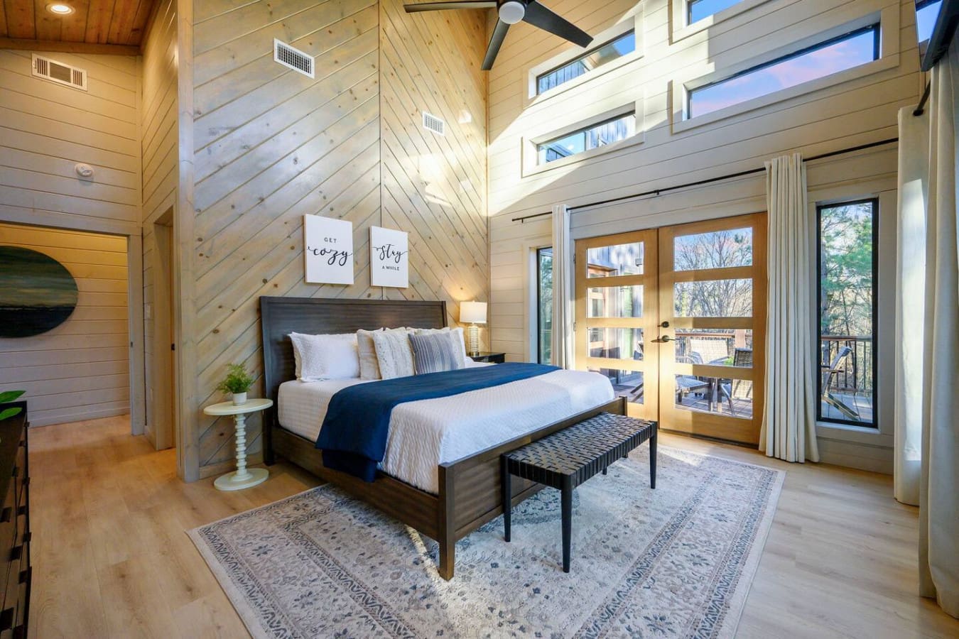 This gorgeous primary bedroom has soaring ceilings, skylights, and direct access to an outdoor deck with tree views.