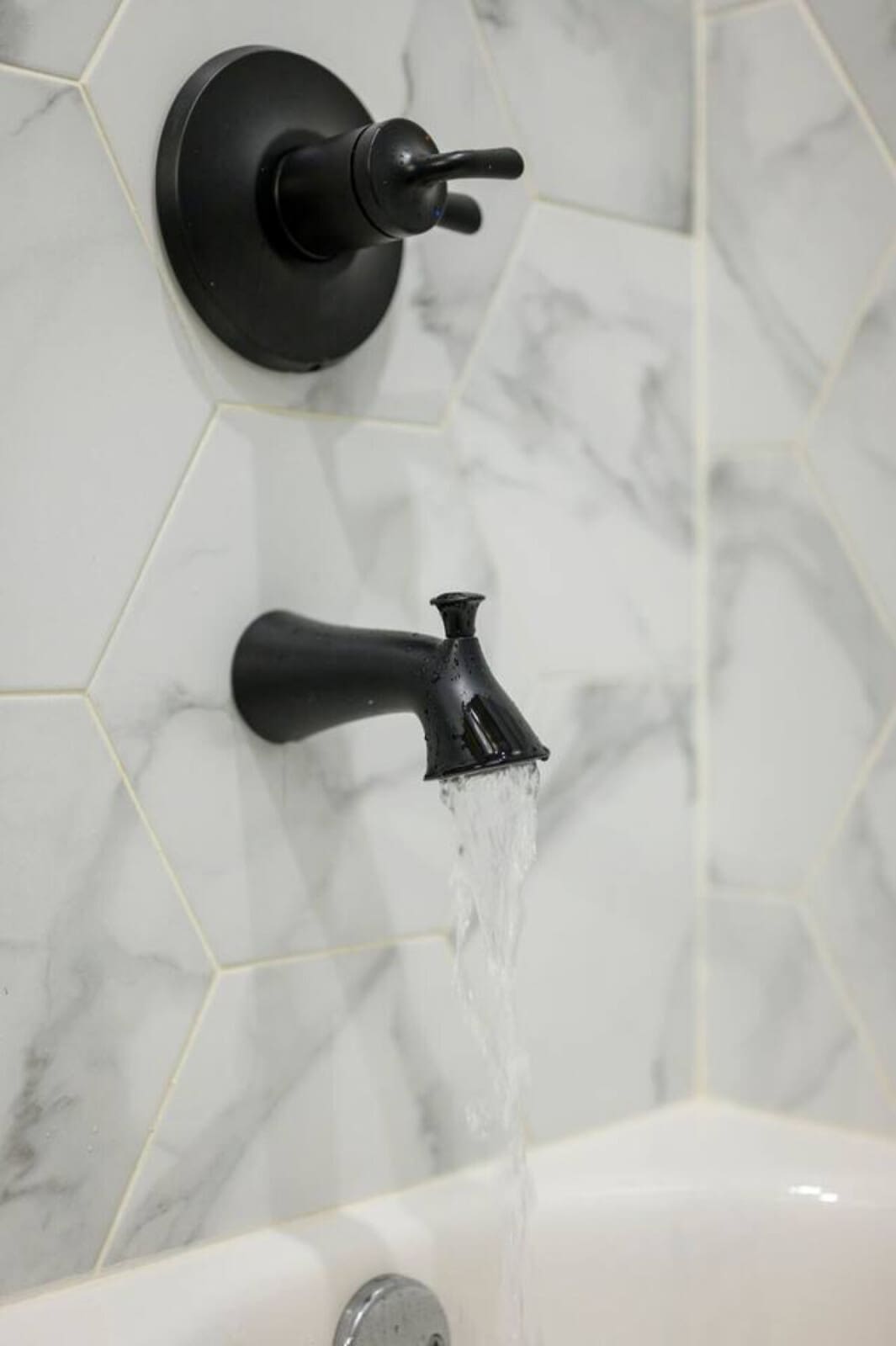 Black matte fixtures and marble tile make the shower feel like a spa retreat.