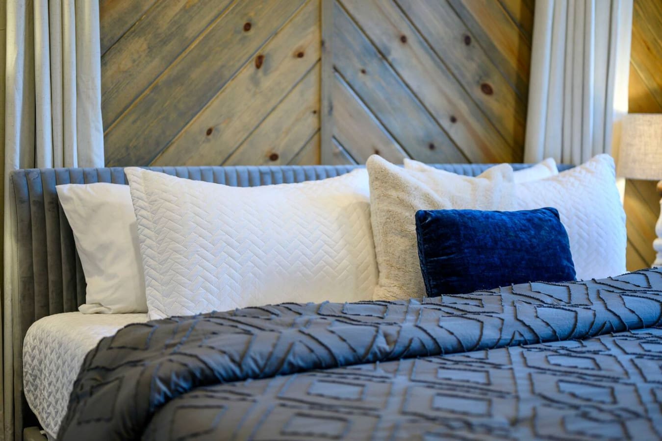 Cozy bed with crisp linens and a rustic wood accent wall that gives major cabin vibes.
